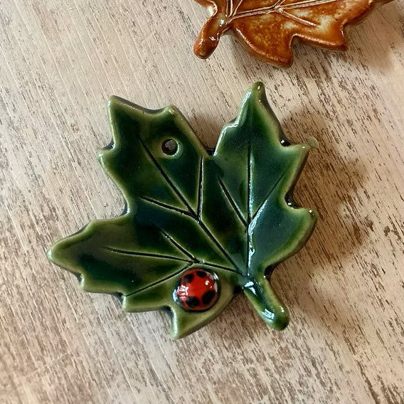 green glazed ceramic leaf Christmas decoration with a tiny ladybug detail by Chloe Charlett handmade in glasgow scotland